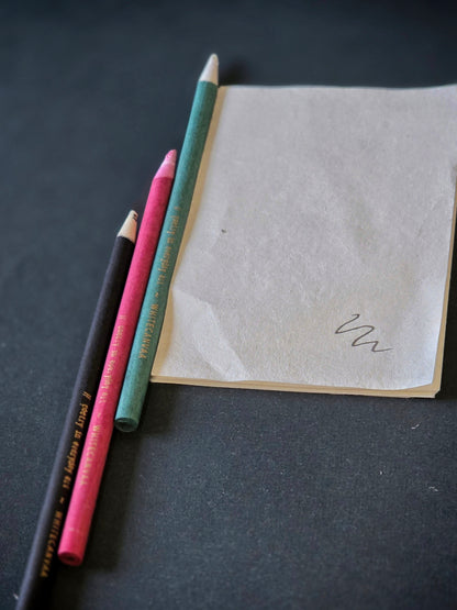 Three different eco friendly pencils made from old newspapers in black, pink and green with gold print by White Canvaa India.